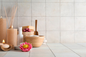 Burning candles, flower and spa supplies on light background