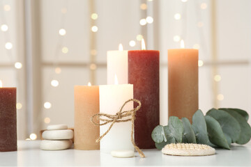 Burning candles and spa stones on light background