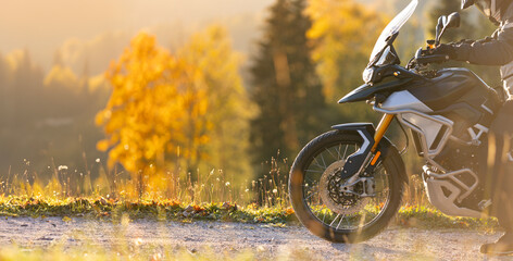Driver posing on motorcycle during sunrise, autumn mountains