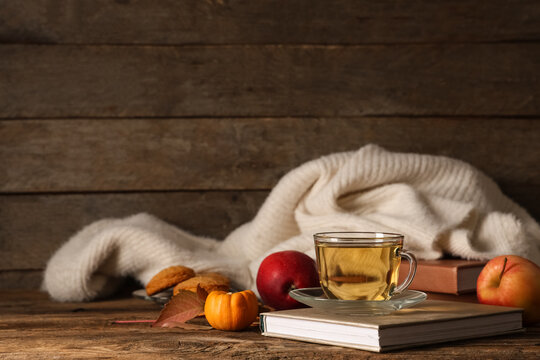 Composition with cup of green tea, notebook and sweater on table near wooden wall