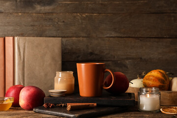 Composition with cup of green tea, notebooks and apples on table near wooden wall