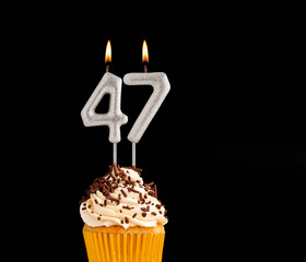 Number 47 shaped candles - Birthday cupcake on black background.