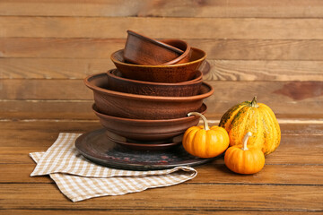 Stack of brown dishes with pumpkins on table against wooden background