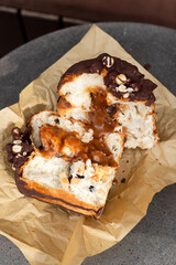 Deliciously drizzled chocolate covered pastry filled with caramel, resting on parchment paper in a cozy café setting