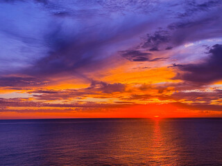 Colorful sunset sky over dark ocean at night. 