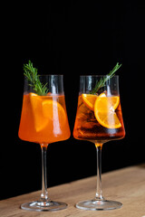 Two refreshing cocktails with orange slices and rosemary garnishes served in elegant glasses against a dark background