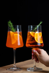 Two refreshing cocktails garnished with orange and rosemary enjoyed in a dimly lit setting