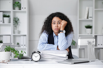Tired African-American businesswoman trying to meet deadline at table in office
