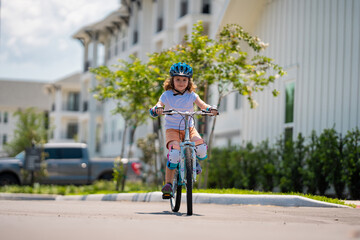 Kids first bike. Child learning to ride bike. Kid riding bike in a helmet. Child with a childs bike and in protective helmet. Articles on safety and summer activity. Happy kid boy having fun in park.