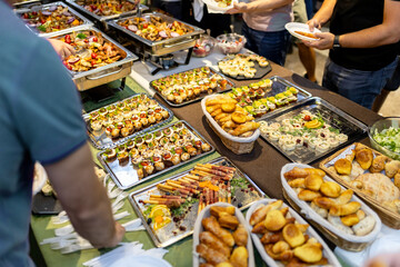 Catering buffet spread featuring a variety of appetizers at an event in a lively setting during a summer evening gathering