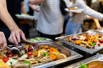 Guests enjoy a buffet featuring a variety of colorful dishes at a lively gathering in the evening