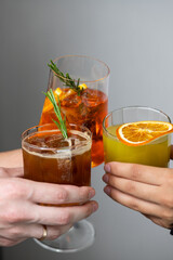 Friends clink glasses filled with colorful cocktails while celebrating together indoors