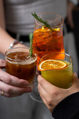 Three friends enjoying colorful cocktails together in a cozy setting with fresh garnishes during an evening gathering