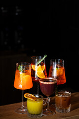 Colorful cocktails arranged beautifully on a wooden bar countertop in a dimly lit ambiance during evening hours