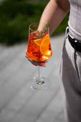 A refreshing cocktail with orange garnish enjoyed outdoors in bright sunlight during a casual afternoon gathering