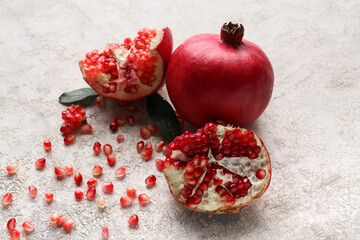 Fresh ripe pomegranates with leaves and seeds on grey background