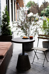 Cozy outdoor café setup with a small round table, a pastry, and a drink on a sunny day in an urban setting