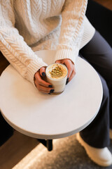 A person enjoying a cozy beverage while seated at a small table in a warm cafe on a chilly afternoon