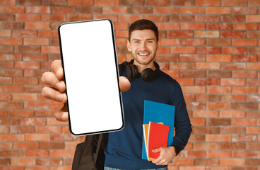 Modern Student. Happy Guy With Backpack Holding Smartphone And Notebooks Smiling To Camera Standing...