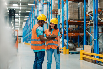 Warehouse workers discussing logistics using clipboard and barcode scanner