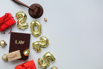Figure 2025 with judge's gavel, law book, gifts and Christmas balls on grey background