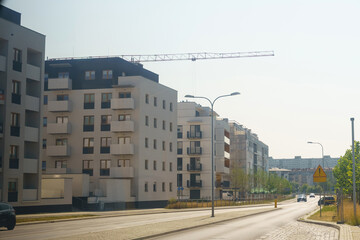 New apartment buildings rise along the sunny street under a clear blue sky