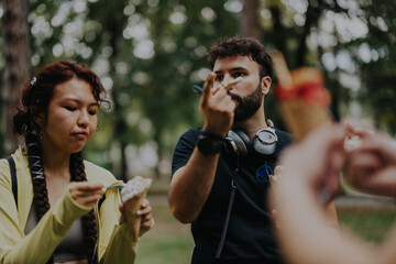 A group of university students and a professor enjoy an ice cream break in a park. The casual...