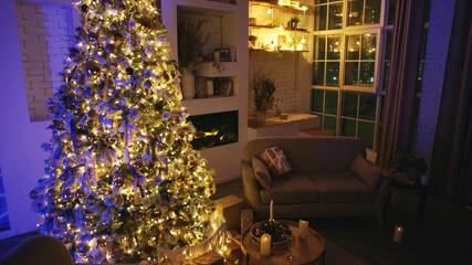 Cozy living room at night with a glowing christmas tree, fireplace, and city lights view, creating a warm festive atmosphere