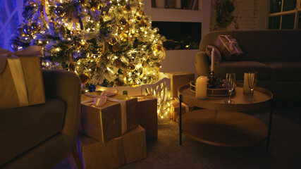 Christmas tree is illuminating a living room with its warm fairy lights, surrounded by elegantly wrapped presents. Two champagne flutes are standing on a coffee table, ready to be enjoyed