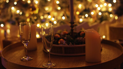 Two empty champagne glasses stand on a table with christmas lights sparkling in the background, evoking a festive and cozy atmosphere
