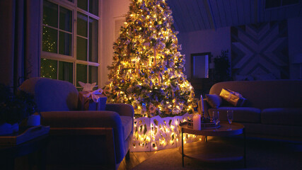 Cozy living room is glowing in the evening with warm christmas lights illuminating the decorated tree and wrapped presents