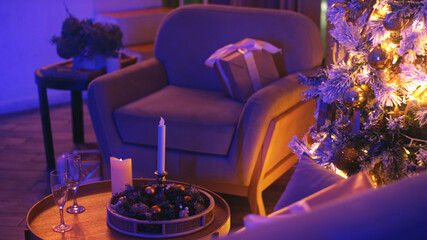 Decorated christmas tree is casting a warm glow on a cozy living room, setting a magical ambiance for the holiday season with candles and champagne glasses adding to the festive atmosphere