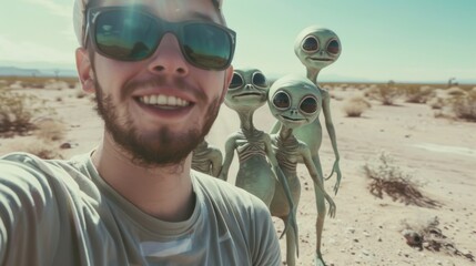 A man wearing sunglasses smiles while taking a selfie with three cartoon-style aliens in a sunny desert landscape, showing a blend of humor and imagination.