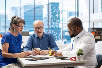 Elderly couple discussing about retirement plans with a financial planner, covering savings strategy and pension options. Middle aged people looking to invest to secure their budget.