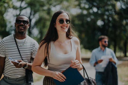 A group of cheerful business people enjoy a sunny day in the park, engaging with each other and exuding positivity and teamwork. Ideal for concepts of collaboration and outdoor meetings. - Powered by Adobe
