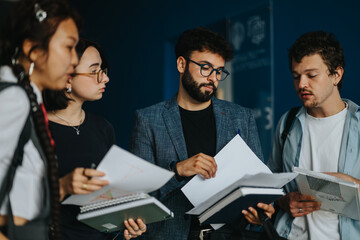 A group of students engaged in a discussion with their professor, reviewing notes and exchanging...
