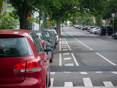 Modern street design with cars parked in outdoor marked parking bays, a bike lane, and speed bumps. suburban road infrastructure with organized on-street car parking. Melbourne, VIC, Australia.