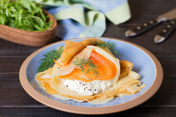 Pancake wrapped with cream cheese and smoked salmon. Crepe.