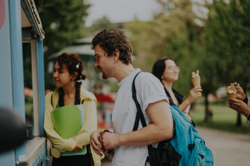 A group of multicultural students relaxes in a park, enjoying ice cream and leisure time between classes. The picture captures friendship and diversity in a natural outdoor setting.