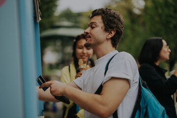 A diverse group of students enjoy a break between classes in the park, savoring ice cream and...