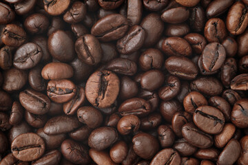 A close-up photograph of roasted coffee beans. The beans are dark brown, with visible texture and...