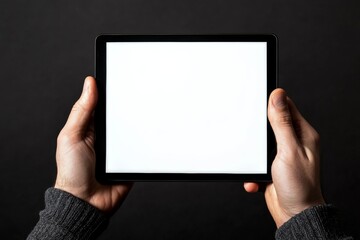 A man holding a tablet with a blank screen against a dark background in a cozy indoor setting