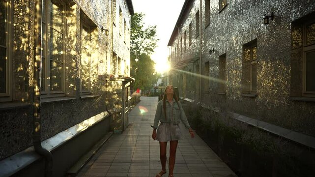 Sunlit Mirror Street in Lodz, Poland: Girl Walking Among Reflective Urban Walls