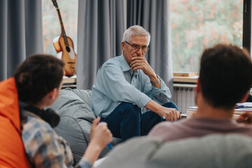A professor sits with students in an informal setting, fostering an engaging learning environment. They appear to be in deep conversation, promoting critical thinking and collaboration.