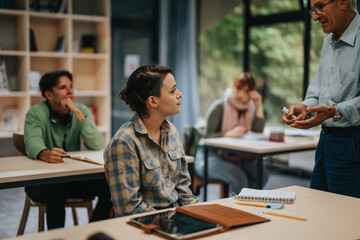 A group of students attentively listening to an elderly professor during a classroom discussion, capturing the essence of education and interactive learning.