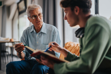 An elderly man offering advice and guidance to a young student during a study session, highlighting...