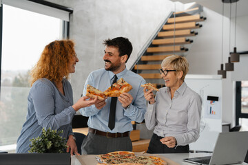Hungry business people eating pizza at break time in office