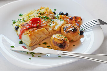 Bacalhau assado com batatas ao murro no prato.