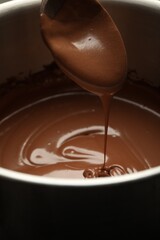 Chocolate dough dripping from spoon into bowl, closeup