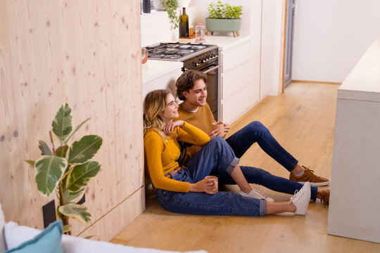 Couple relaxing on kitchen floor, enjoying cozy time together at home